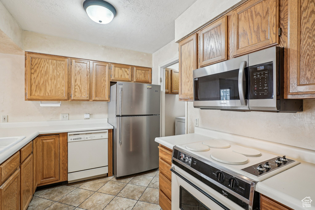 Kitchen with appliances with stainless steel finishes, a textured ceiling, and light countertops