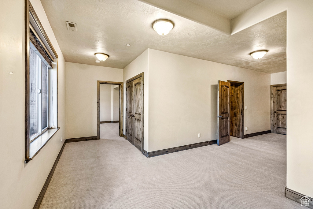 Spare room featuring baseboards, a textured ceiling, and light colored carpet