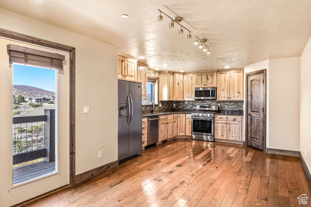 Kitchen featuring stainless steel appliances, light brown cabinets, dark countertops, and recessed lighting