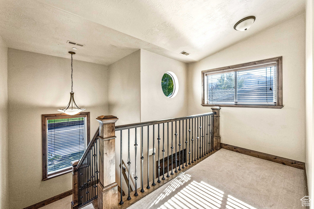 Hall with baseboards, carpet floors, an upstairs landing, and lofted ceiling