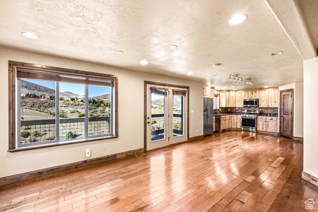 Unfurnished living room featuring baseboards, recessed lighting, dark wood finished floors, and a textured ceiling