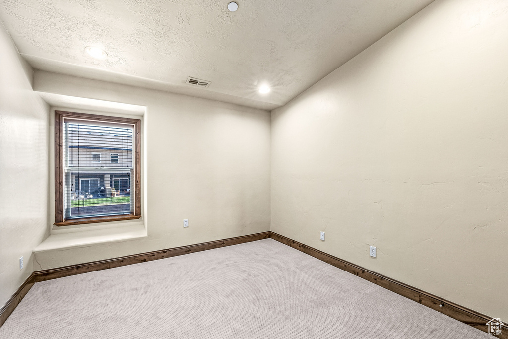 Carpeted empty room featuring baseboards and a textured ceiling