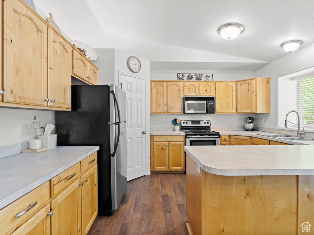 Kitchen with appliances with stainless steel finishes, a sink, lofted ceiling, light brown cabinetry, and light countertops