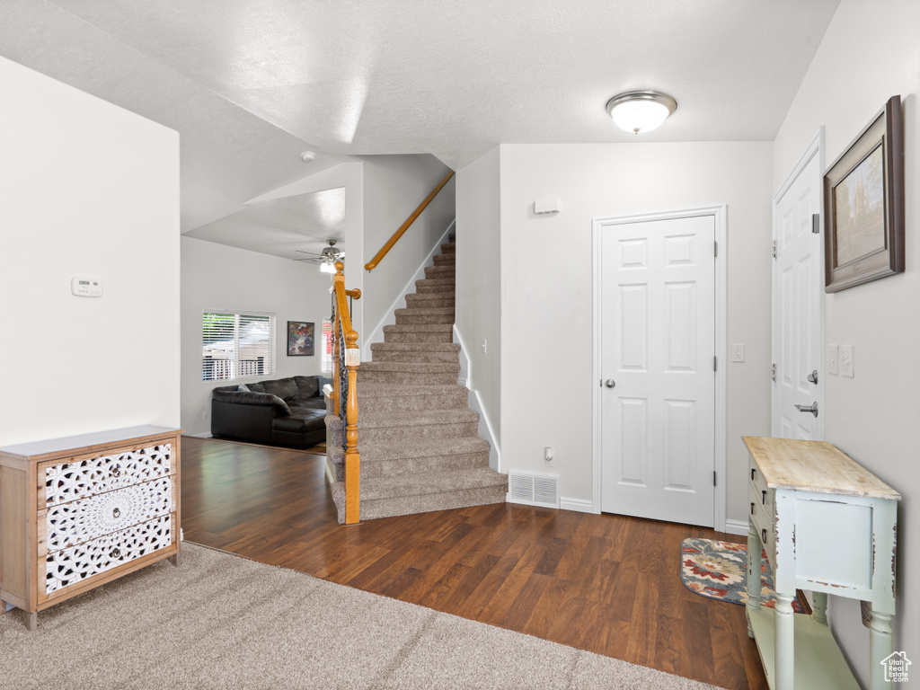 Foyer entrance featuring stairs, dark wood-type flooring, a ceiling fan, and baseboards