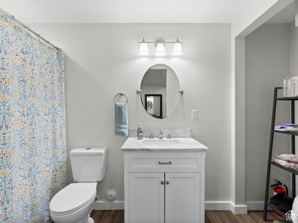 Full bath featuring wood finished floors, toilet, baseboards, vanity, and a shower with shower curtain