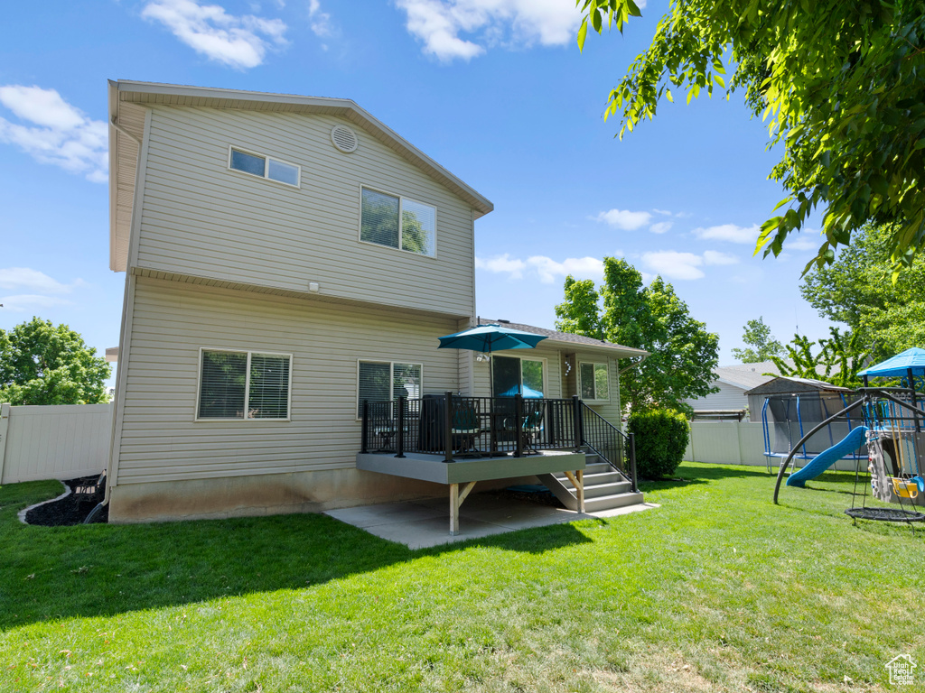 Back of house featuring a wooden deck and a playground