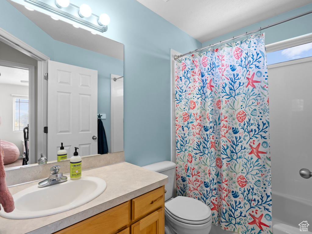 Bathroom with toilet, a shower with shower curtain, and vanity