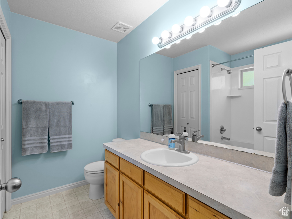 Full bathroom featuring vanity, toilet,  shower combination, and baseboards