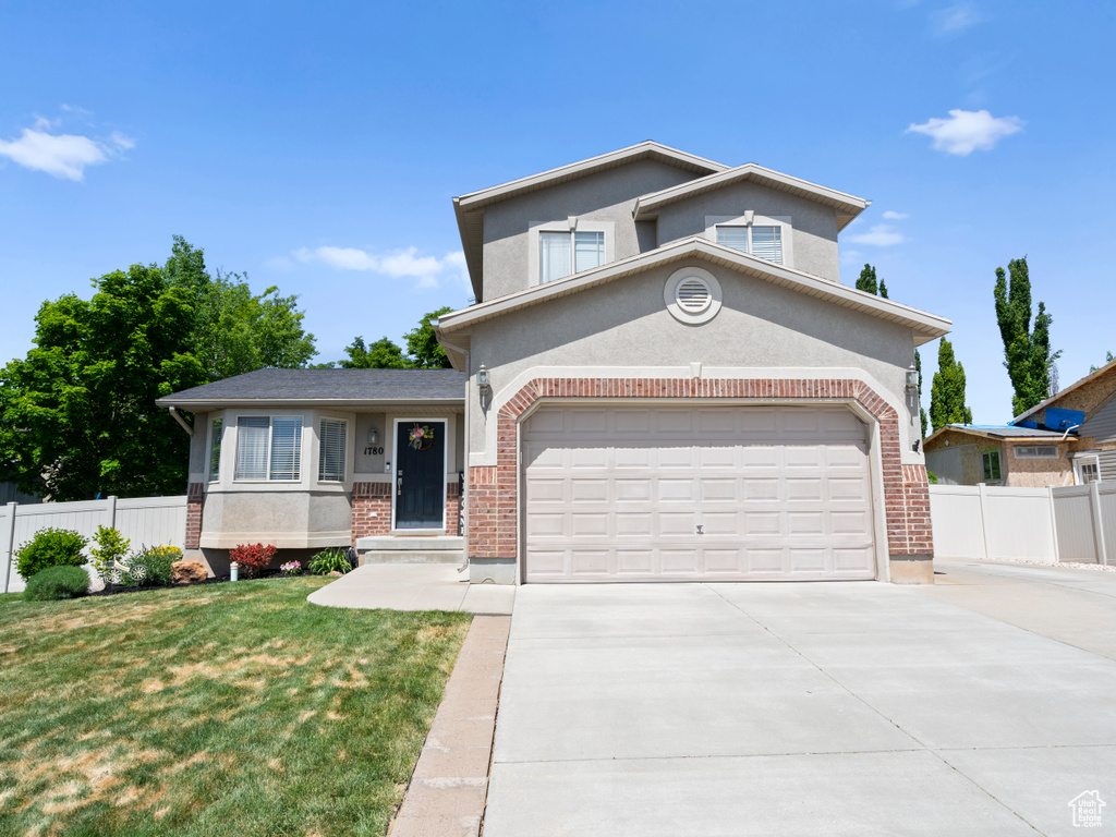 View of front of property featuring brick siding, driveway, and stucco siding