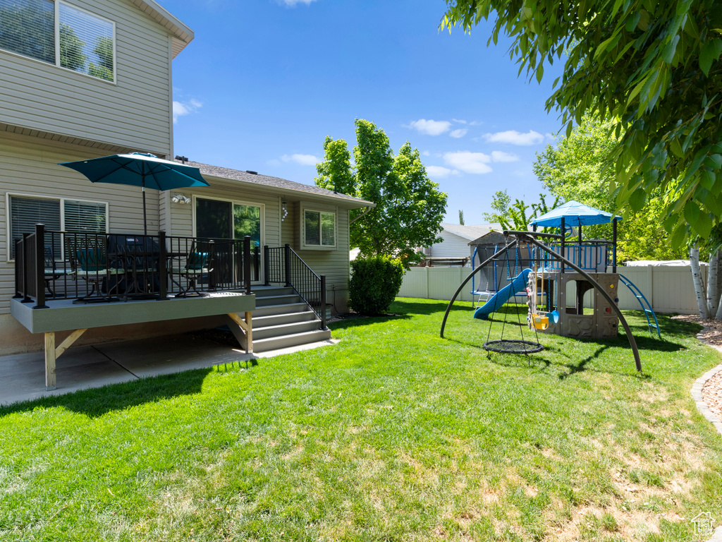 View of yard with a playground and a wooden deck