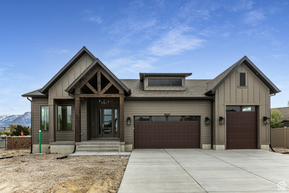 View of front of property with board and batten siding, a garage, driveway, a mountain view, and a shingled roof