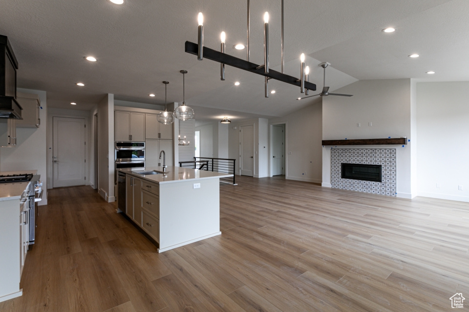 Kitchen with a sink, a center island with sink, open floor plan, recessed lighting, and stainless steel stove