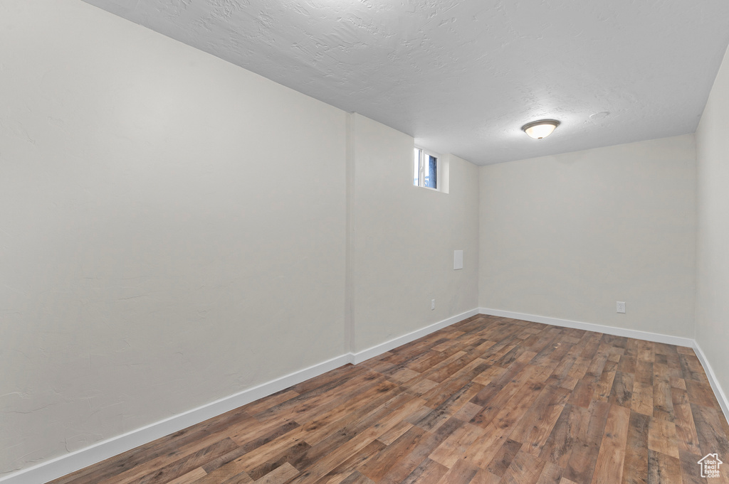 Below grade area with baseboards, wood finished floors, and a textured ceiling