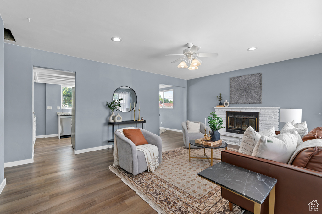Living area with a glass covered fireplace, a ceiling fan, recessed lighting, baseboards, and wood finished floors