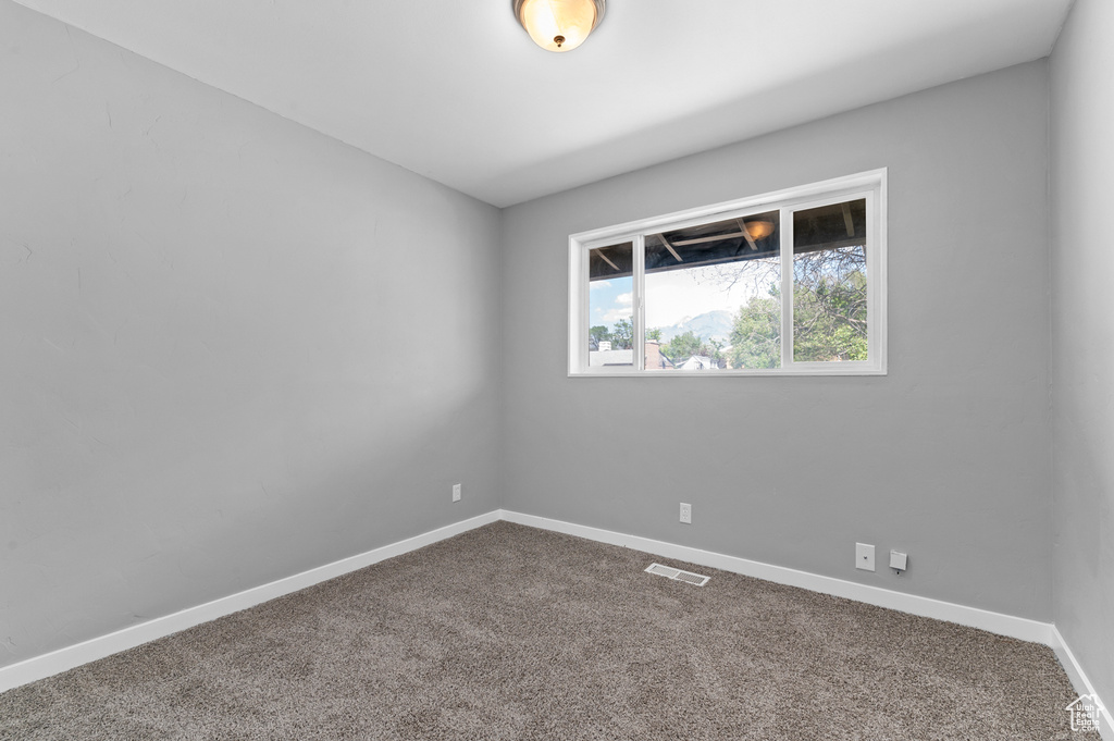 Spare room featuring dark carpet and baseboards