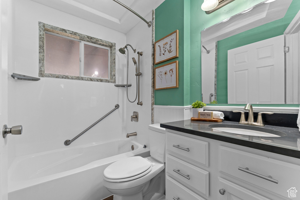 Full bath featuring toilet, shower / tub combination, vanity, and a wainscoted wall