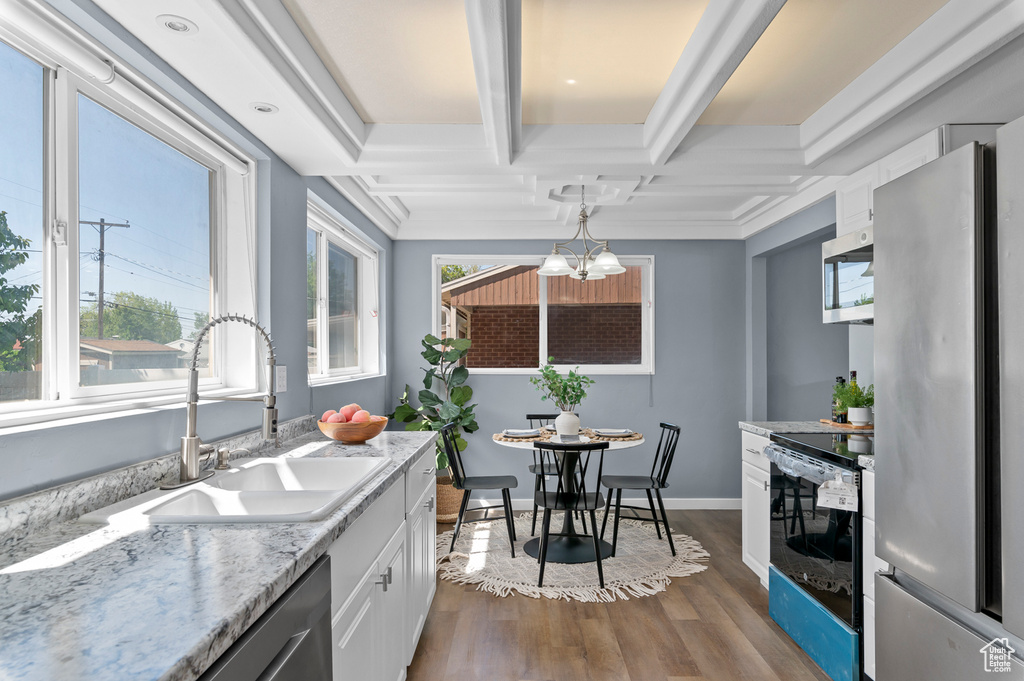 Kitchen featuring appliances with stainless steel finishes, a sink, coffered ceiling, wood finished floors, and white cabinets