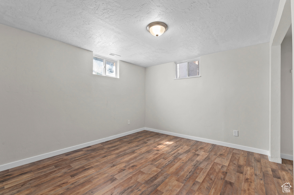 Below grade area featuring wood finished floors, baseboards, and a textured ceiling
