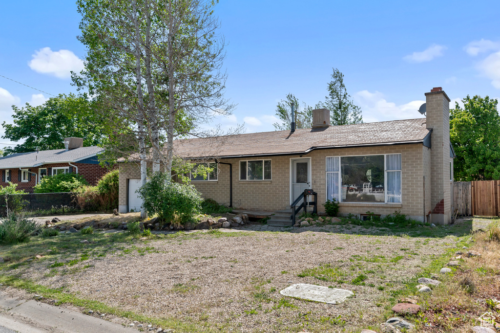 Ranch-style house featuring fence, brick siding, a chimney, an attached garage, and cooling unit