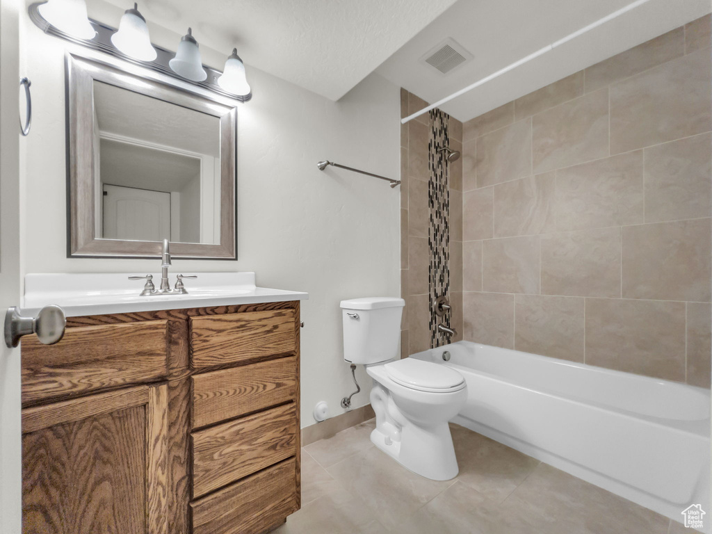 Full bathroom with tile patterned floors, toilet, vanity, shower / tub combo with curtain, and baseboards