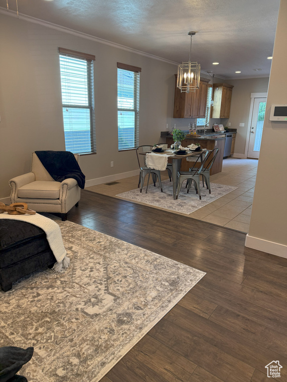 Dining room with a chandelier, baseboards, light wood finished floors, ornamental molding, and recessed lighting
