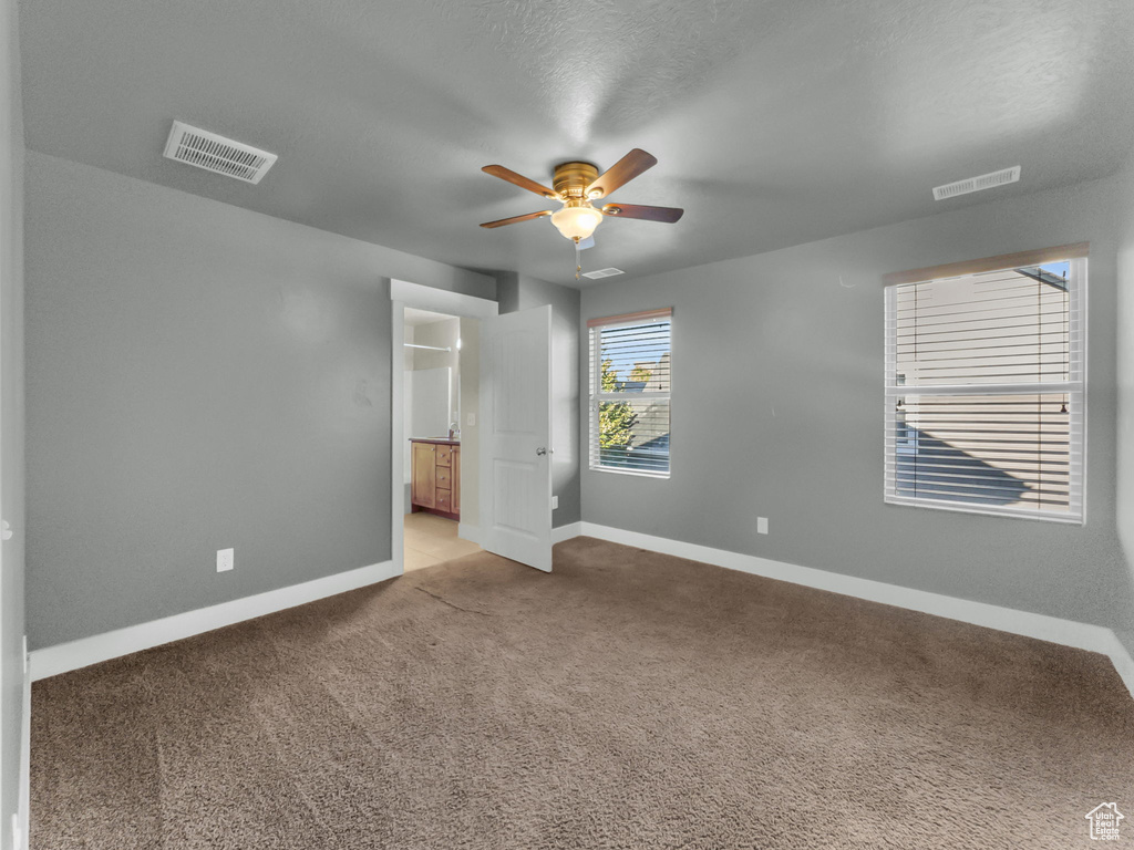 Unfurnished bedroom featuring baseboards, carpet floors, a ceiling fan, and ensuite bath