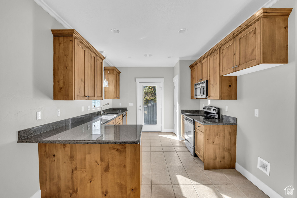 Kitchen featuring appliances with stainless steel finishes, brown cabinetry, light tile patterned floors, a peninsula, and crown molding
