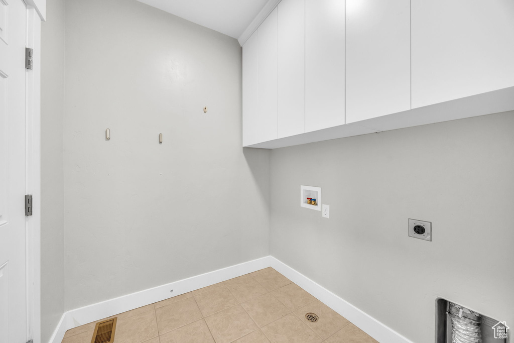 Laundry room with cabinet space, electric dryer hookup, washer hookup, light tile patterned flooring, and baseboards