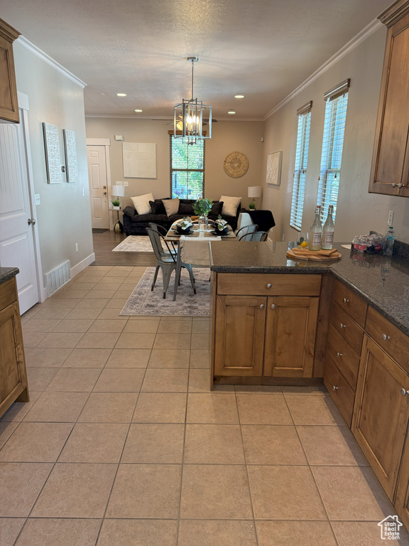 Kitchen with open floor plan, a peninsula, light tile patterned flooring, ornamental molding, and a chandelier