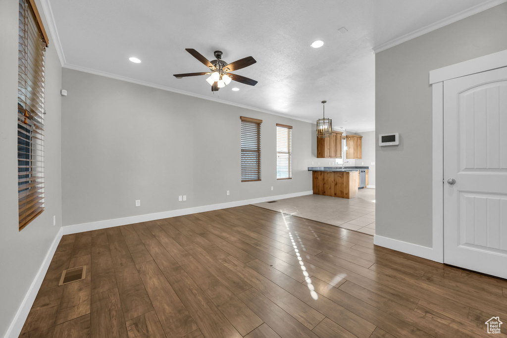 Unfurnished living room with a ceiling fan, ornamental molding, recessed lighting, baseboards, and dark wood-type flooring