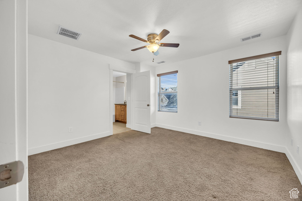 Unfurnished room featuring a ceiling fan, baseboards, and light carpet