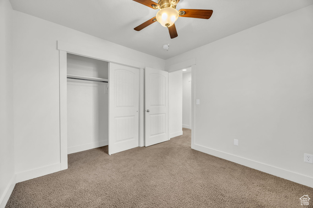 Unfurnished bedroom featuring carpet, baseboards, a closet, and ceiling fan