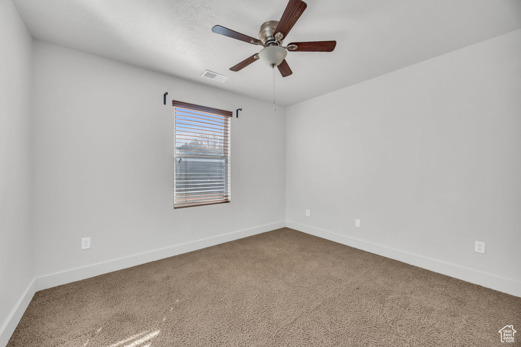 Carpeted empty room featuring a ceiling fan and baseboards