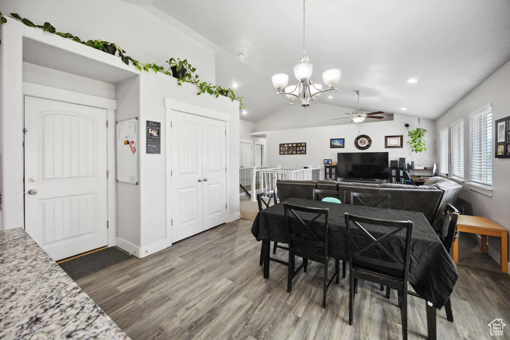 Dining room with ceiling fan, a chandelier, wood finished floors, vaulted ceiling, and baseboards