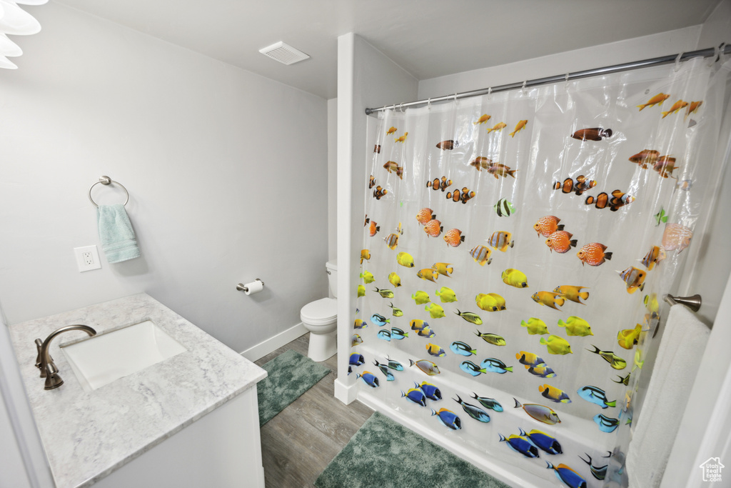 Full bathroom featuring wood finished floors, toilet, vanity, and baseboards