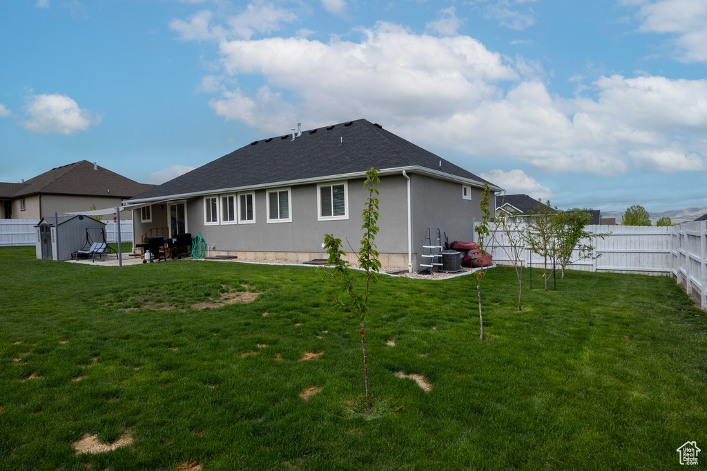 Rear view of property featuring a patio, stucco siding, roof with shingles, and a storage unit