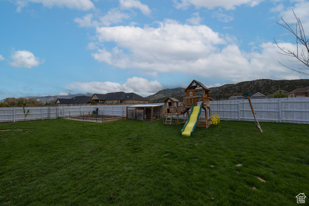 View of yard with a vegetable garden, a playground, and a mountain view