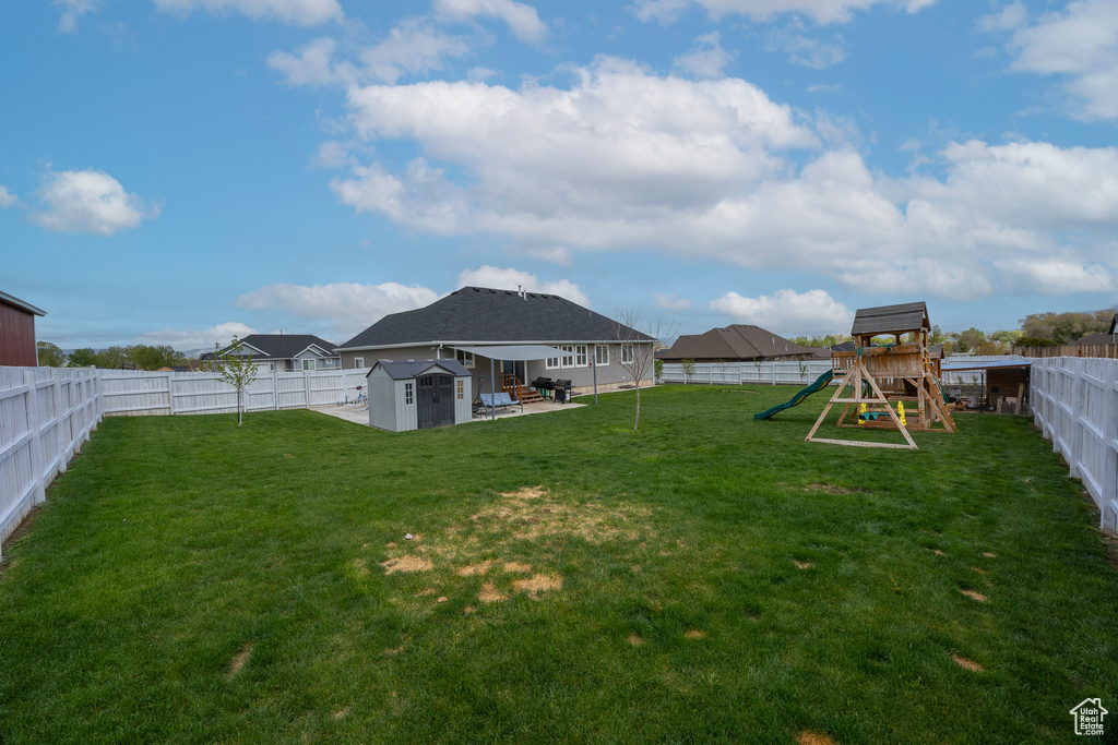 View of yard featuring a shed, a playground, an outdoor structure, and a patio