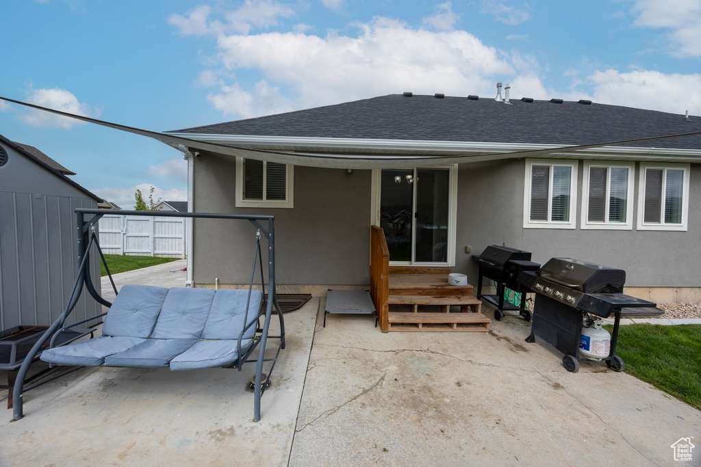 Back of house with roof with shingles, stucco siding, a patio area, and fence