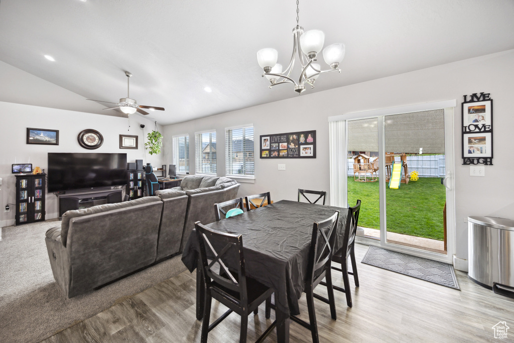 Dining area featuring light wood finished floors, a chandelier, lofted ceiling, and a ceiling fan