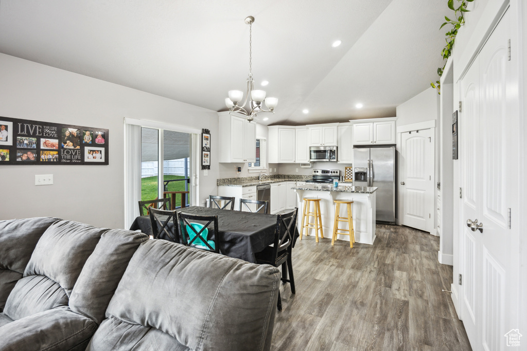 Living area featuring a chandelier, lofted ceiling, recessed lighting, and wood finished floors