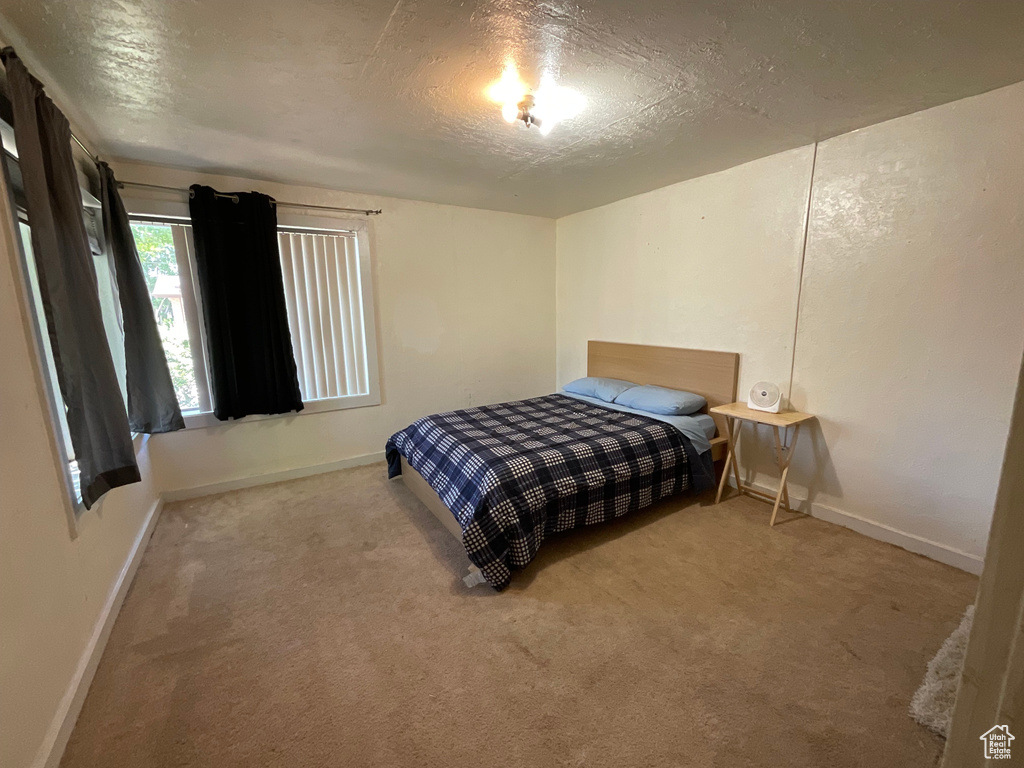 Carpeted bedroom featuring baseboards and a textured ceiling