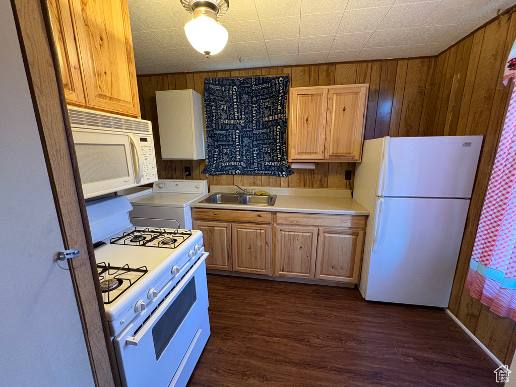 Kitchen with white appliances, washer / clothes dryer, a sink, wooden walls, and light countertops