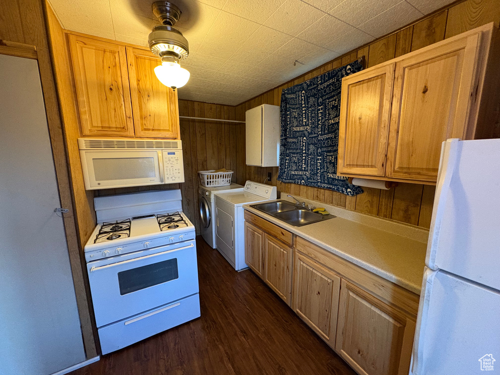 Kitchen featuring white appliances, a sink, washer and clothes dryer, dark wood-style flooring, and light countertops