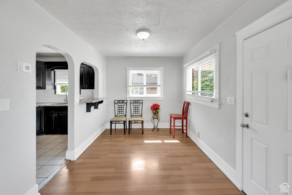 Living area featuring light wood-style flooring, a textured ceiling, arched walkways, and baseboards