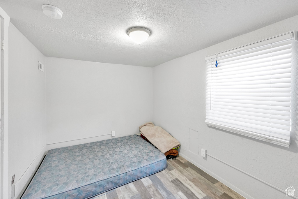 Unfurnished bedroom with light wood-style floors, a textured ceiling, and baseboards