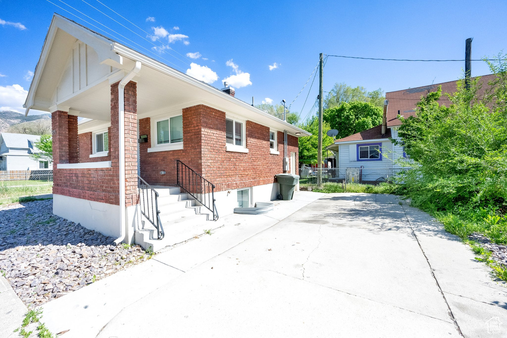 View of side of home with brick siding and fence