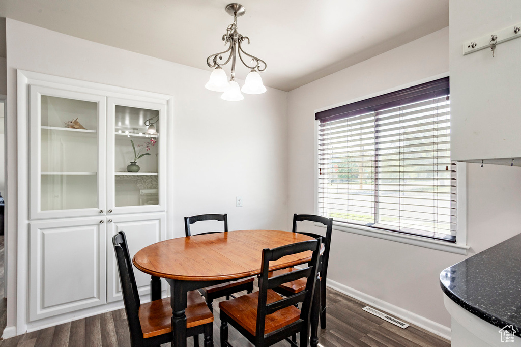 Dining space with dark wood-style floors, baseboards, and a chandelier