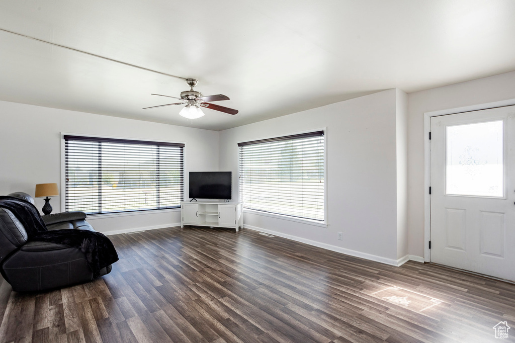 Living room featuring baseboards, dark wood-type flooring, and a ceiling fan