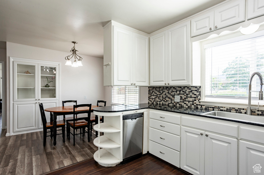 Kitchen featuring stainless steel dishwasher, open shelves, dark countertops, a sink, and tasteful backsplash